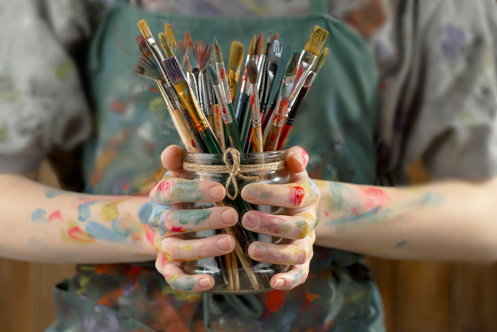 Woman holding a jar of paintbrushes