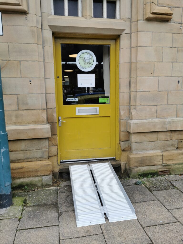 Photo of a yellow door with a portable ramp leading up to it.