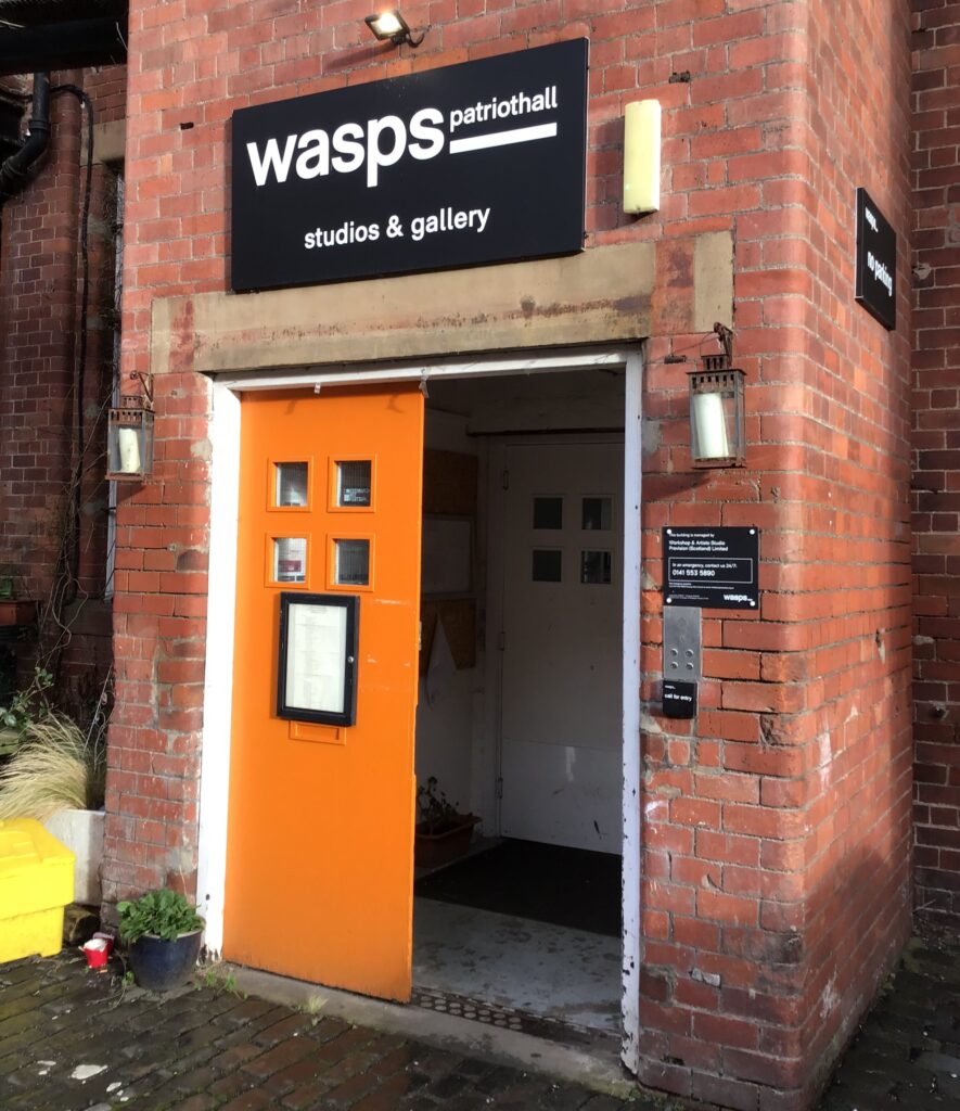 A bright orange doorway with a sign saying "wasps patriothall gallery"